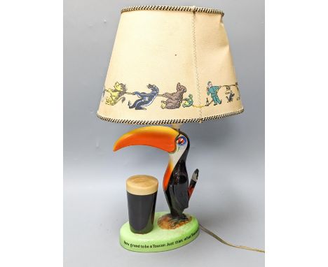 A Guinness toucan lamp, with original shade, tail repairedTotal height including shade 43.5 cm