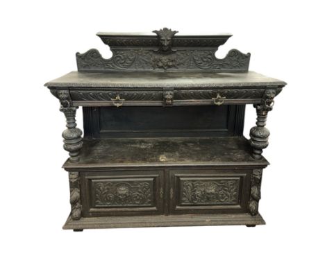 A 19th century carved oak buffet, the upper tier with two frieze drawers and cupboards beneath, with lion and figural carved 