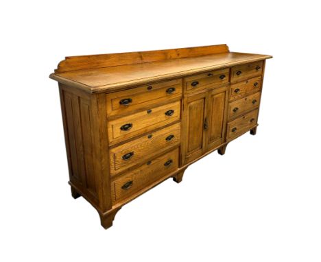 A large early 20th century oak buffet with an arrangement of nine long drawers and central cupboard, 237cms wide.