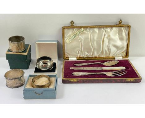 A silver cased child's fork, knife and spoon set; together with three various silver napkin rings; a silver plated napkin rin