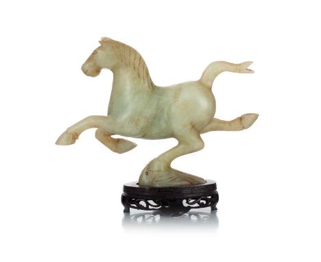 CHINESE JADE FIGURE OF A GALLOPING HORSE, 19TH/20TH CENTURY with reddish-brown inclusions, on hardwood stand21cm wide