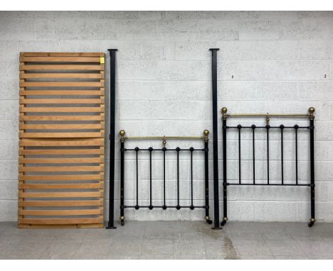 A Victorian bedstead having a brass tubular top rail with two ball finials set onto a cast iron gate style headboard with mou