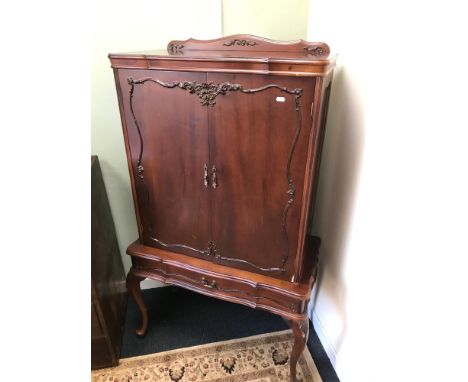 A Reproduction drinks cabinet. Styled with Cabriole legs. Fitted glass shelf interior and single under drawer. Measures 148x8