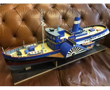 A Large model of a paddle steam boat. The boat is named Fantasia. Hand built, Highly detailed. Displayed on a wooden stand. m