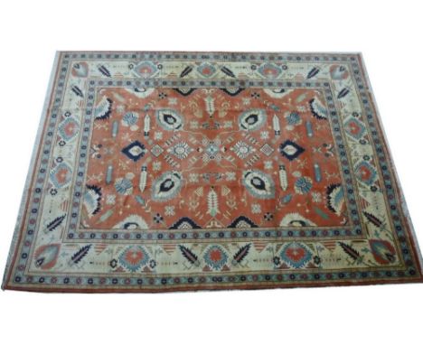 A Heriz carpet with salmon pink ground decorated with leaf motifs in pale blue, cream, dark blue, and beige, wide cream folia