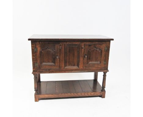 A reproduction oak cabinet on stand the rectangular top above a fielded panel flanked by ogee arched fielded panel doors rais