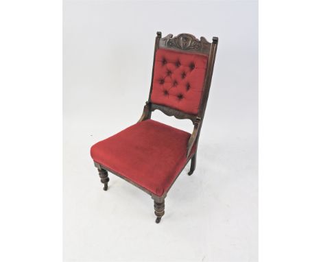 An Edwardian stained beech nursing chair, with foliate carved top rail and later upholstered claret button back and overstuff