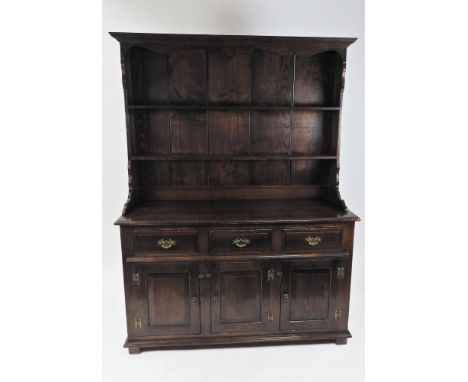 A reproduction oak dresser, the ogive cornice above a shaped canopy and two shelves with enclosed rack above a rectangular to