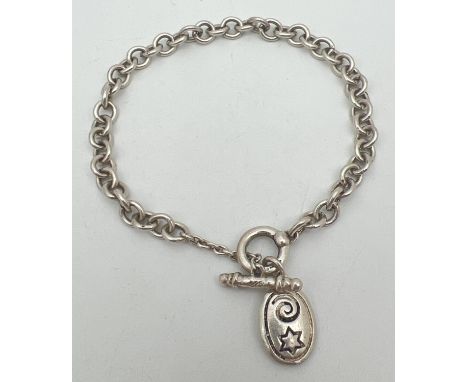 A silver belcher style chain bracelet with T bar clasp and oval charm decorated with star &amp; swirl detail. Silver marks to