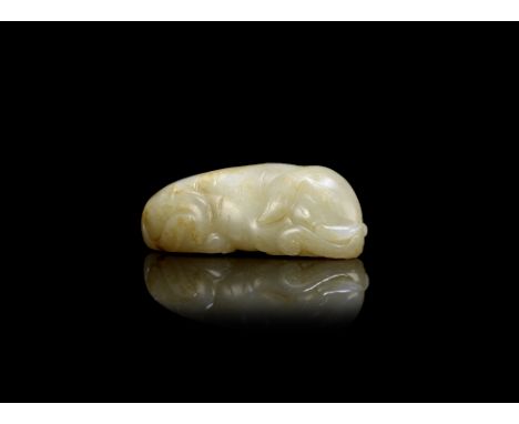 A pale green jade carving of a recumbent elephantThe trunk flicked to the right side, the body incised to simulate the hide, 