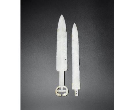 Two archaistic white jade ceremonial swordsThe first, thinly carved as a full sword with confronting snake pommel, with incis