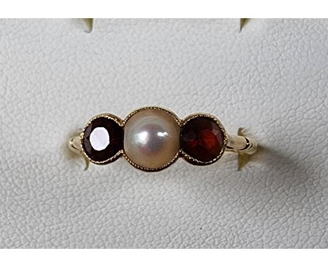 An 18ct gold garnet and pearl three stone ring, Birmingham 1946, size O, 2.2 gm 