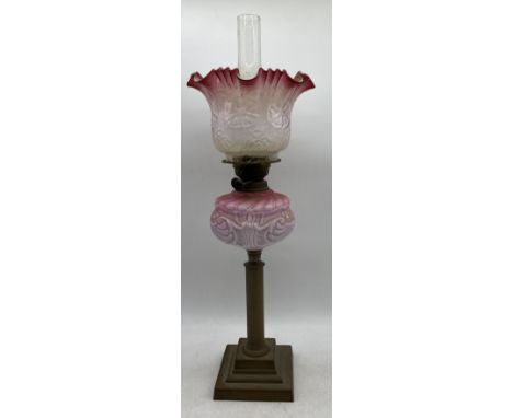 A Victorian oil lamp with cranberry glass shade (chip to base of shade)