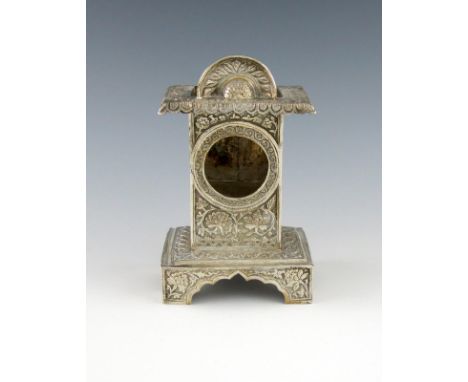 An Indian electroplated watch holder, rectangular form, raised pediment, chased foliate scroll decoration, on a raised rectan