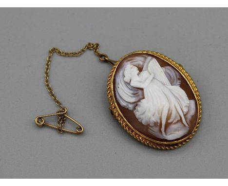 A hallmarked 18ct gold shell cameo brooch. Depicting a woman in a flowing dress, playing a lute. Overall length approximately