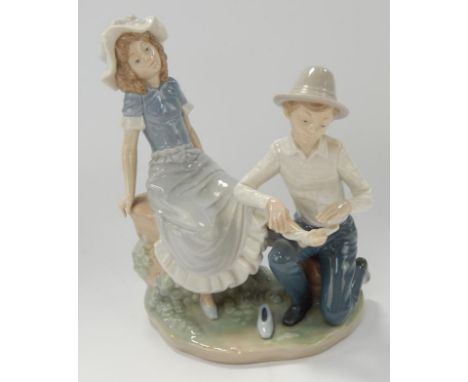 A Nao porcelain figure group, of a young girl seated having her foot bandaged by a boy kneeling at her feet, 23cm high.