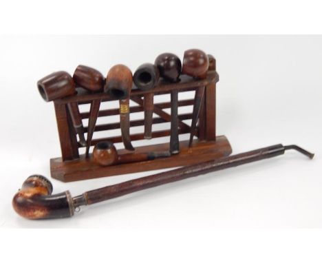 An early 20thC pipe rack, with assorted briar and other pipes.
