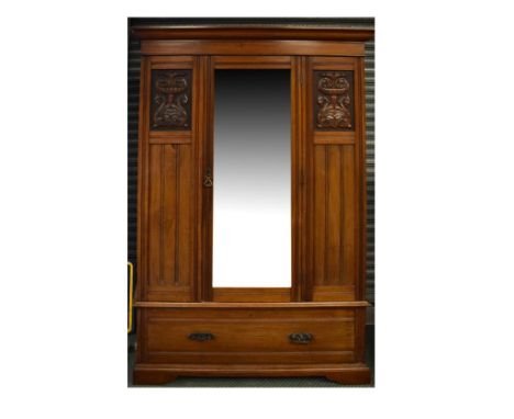 Edwardian walnut wardrobe having a bevelled mirrored panel door flanked by partially carved panels, one long drawer to the ba