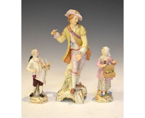 Pair of late Meissen/Dresden porcelain figures modelled as a servant holding a tazza and carafe, and a lady vendor, underglaz