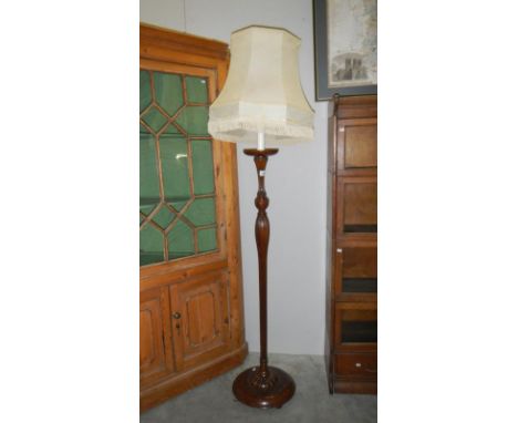 A wooden standard lamp with shade