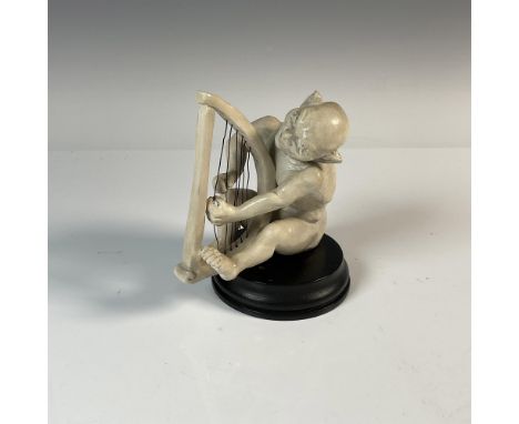 Stoneware modelled seated creature playing the harp in a matt white glaze. Placed on a wood base. Incised Martin Bros, London