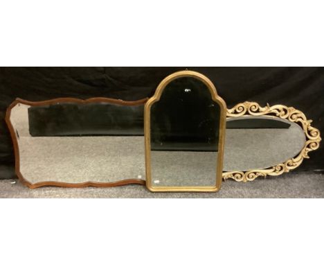 An arched gilt mirror, 64cm high;  an oval mirror;  76cm high;  another mahogany (3) 