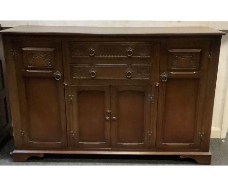 A mid 20th century oak sideboard, oversailing rounded rectangular top, above an arrangement of two short drawers, two tall cu
