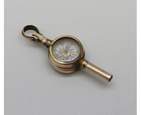 An antique yellow metal pocket watch key set with a compass and intaglio, compass hand loose, 2.3g