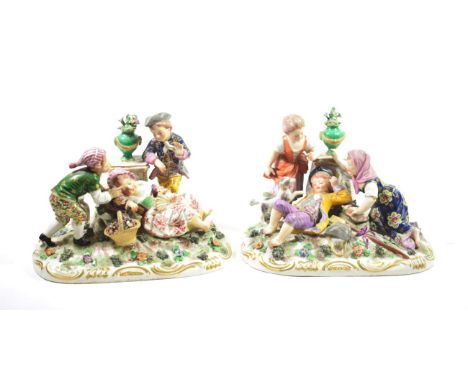 A Pair of Derby Style Porcelain Figure Groups, late 19th/early 20th century, as children playing beside urns of flowers on mo