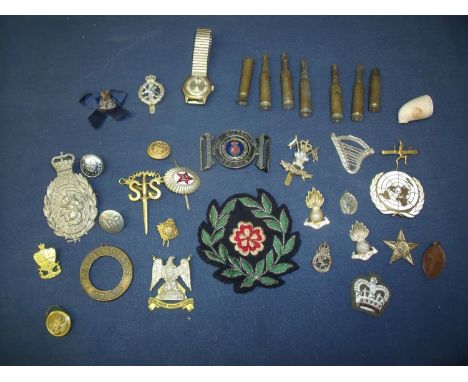 Box containing a selection of various assorted military badges including cloth and metal cap badges, belt buckles, small sele