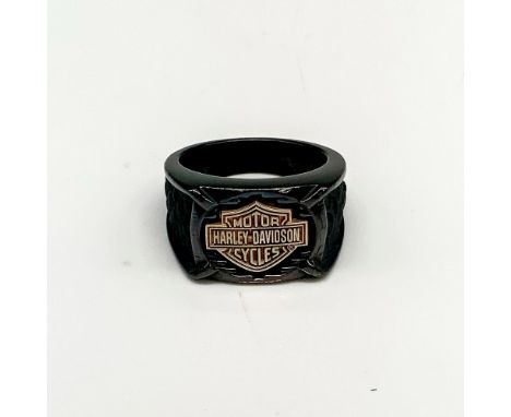 Black band with a large copper tone Harley Davidson logo in the front and textured dark grey scales carved on either side. Ti