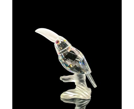 Clear faceted crystal figure of a toucan with blue/green/pink eyes frosted beak, perched on a frosted crystal base. Part of t