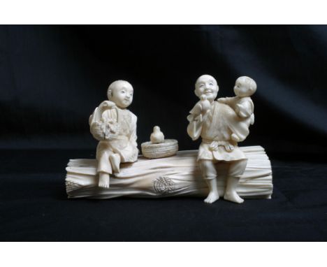 A 19th Century carved ivory Okimono figure group, figures on a tree trunk. Measures 9 cm