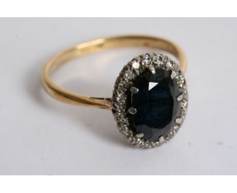 An 18ct gold ring set with a sapphire in diamond surround