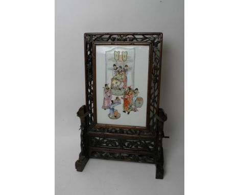 A Chinese porcelain panel table screen in carved hardwood surround decorated with figures. Height: 65cm approximately