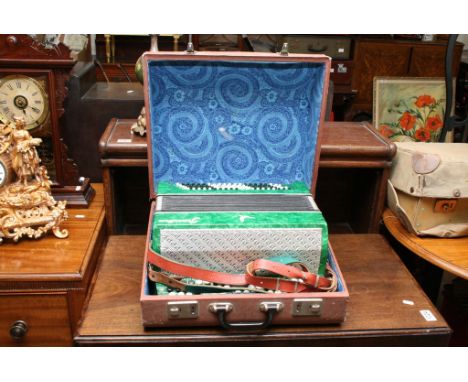 A cased green button accordion 