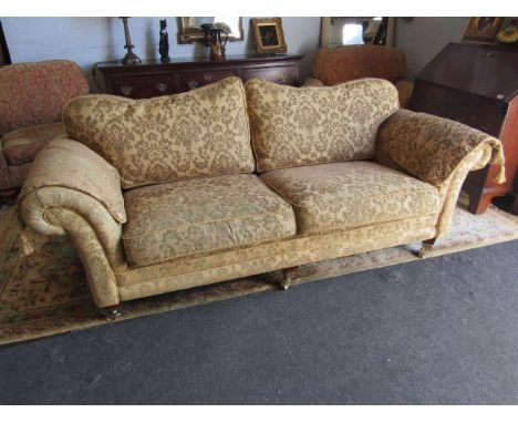 An upholstered swag design three seater sofa with covers on brass capped feet and castors, 95cm deep, 215cm long approx