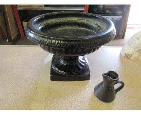 A black ground ceramic urn and miniature jug