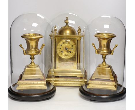 A gilt metal clock garniture, c.1900, with a pair of urns also under glass domes, French movement by A D Mougin, striking on 