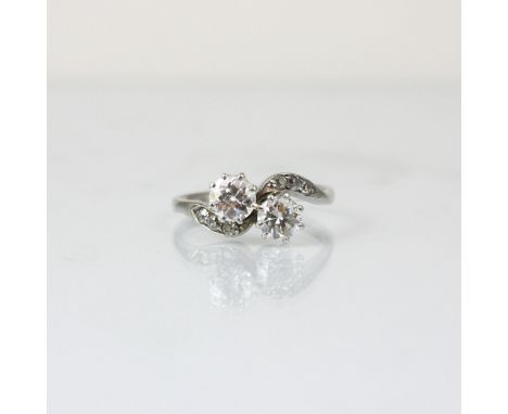 An early 20th century diamond ‘toi et moi’ ring, the old cut and round cut diamond set in white metal claw setting edge, with