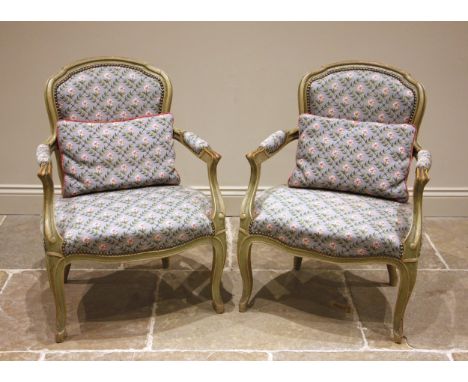 A pair of painted French fauteuil, early 20th century, later re-covered in lattice pattern floral tapestry fabric and applied