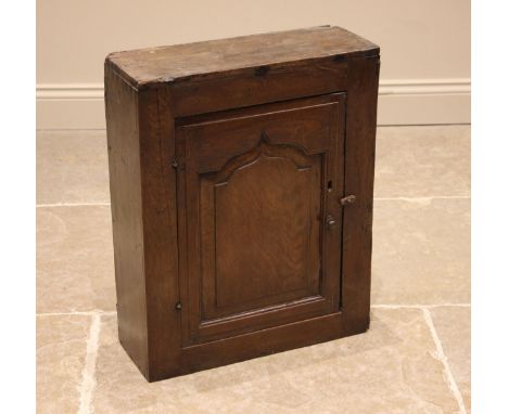 An early 18th century oak mural / spice cupboard, probably Conwy Valley, the single ogee fielded panelled door upon hook and 