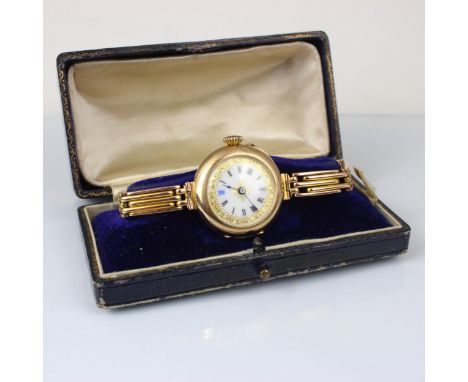 An early 20th century yellow metal wristwatch, the circular white dial with Roman numerals and floral detail, set to plain po