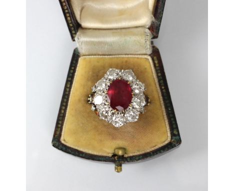 An Edwardian style untested ruby and diamond ring, the central oval cut untested ruby within surround of nine round cut diamo