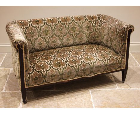 An Edwardian mahogany sofa, in embossed foliate fabric, the padded scroll back rest and arms upon supports centred with a mou