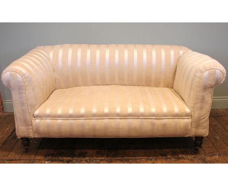 An Edwardian drop-end Chesterfield type sofa, later re-covered in striped ivory coloured fabric, the deep set padded scrolled