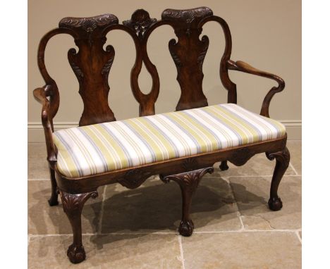 A George II style twin chair back walnut sofa, mid 20th century, the carved shell crest extending to a pair of leaf swept vas