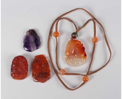 A Chinese carnelian pendant, 20th century, carved and pierced with squirrel, fruit and flowers, length 5.1cm, the cord with c