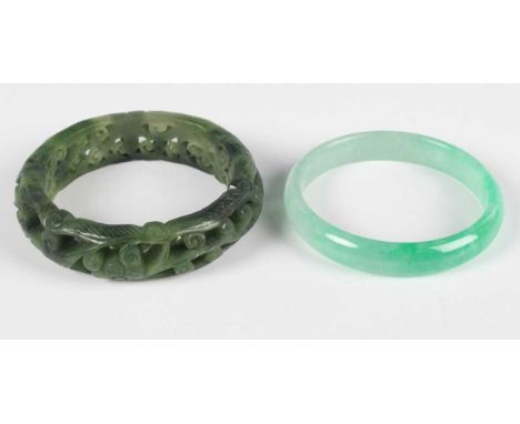 A Chinese jadeite bangle of mottled pale green tone, inside diameter 5.8cm, together with a Chinese spinach green jade bangle