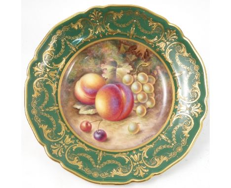 A Royal Worcester tazza, decorated to the centre with a panel of hand painted fruit, by Ayrton, to a deep green and gilt bord